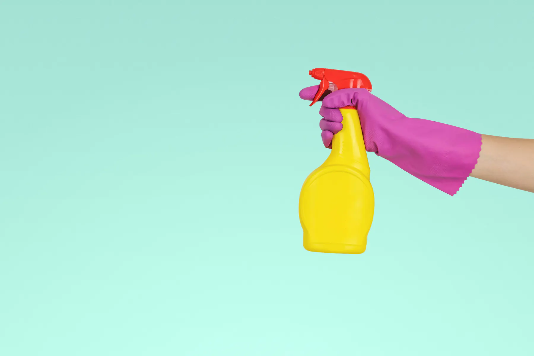 Gloved hand holding a spray bottle, ready to clean